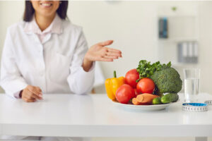 A woman holds an open hand toward a bowl of fresh vegetables