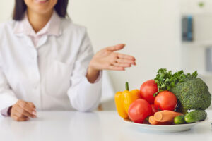 A woman holds an open hand toward a bowl of fresh vegetables