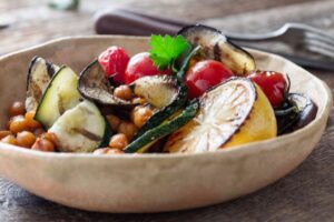 Bowl of grilled zucchini, tomatoes, chickpeas and lemon